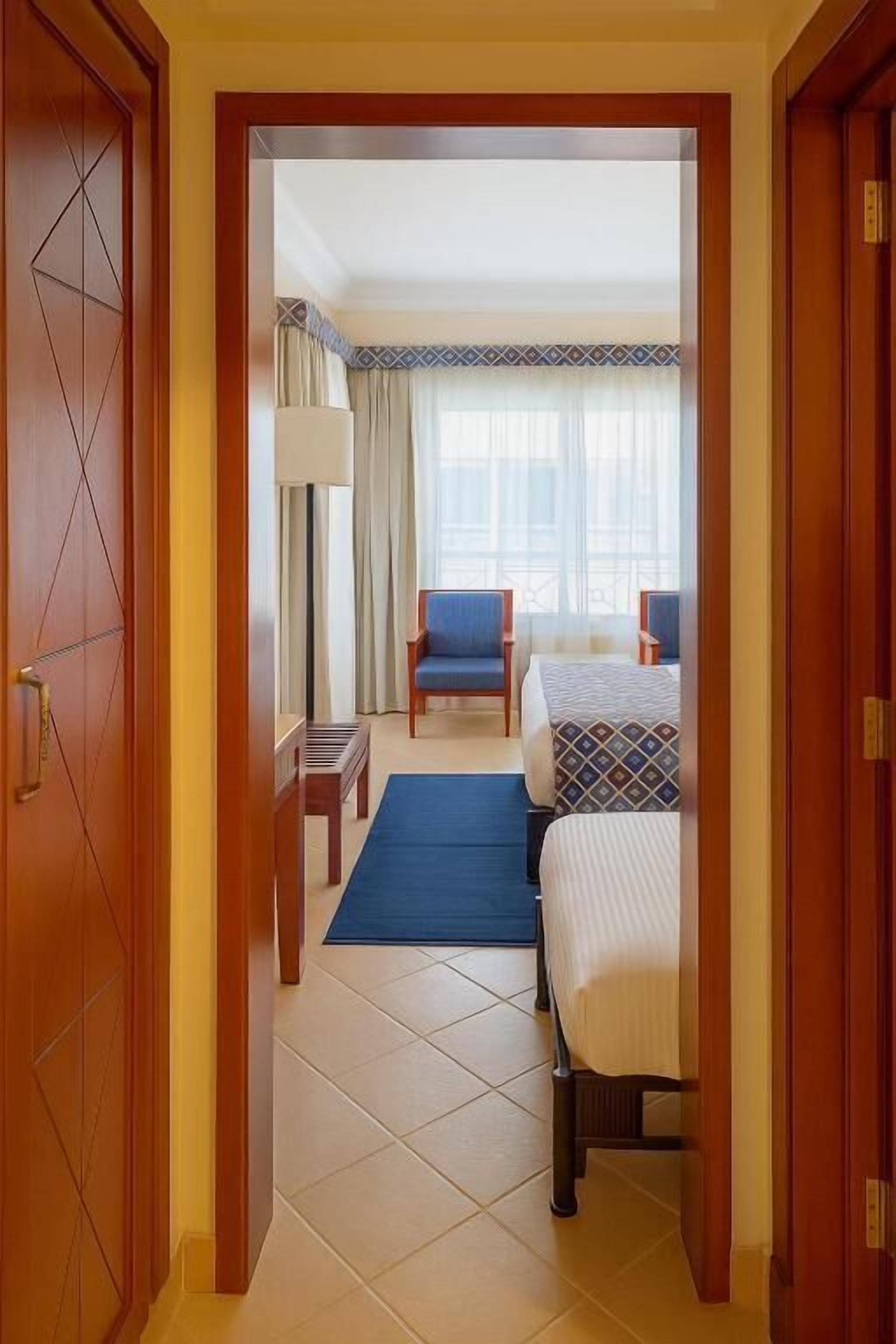 Habitación de hotel con cama, una silla, un escritorio y una ventana con cortinas.