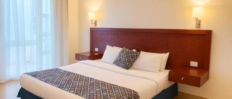 A neatly made bed with a patterned bedspread, two bedside lamps, and a nightstand with a drawer.