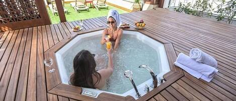Una terraza de madera con un jacuzzi, sillas de descanso y vistas al océano.