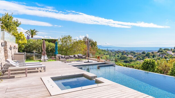 Zona de piscina con sillas de descanso, un jacuzzi y vistas del paisaje.