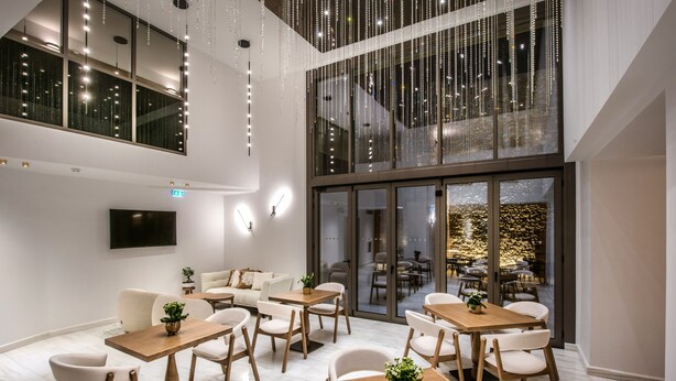 Een moderne eetruimte met houten tafels en witte stoelen, grote ramen en uitzicht op het interieur.