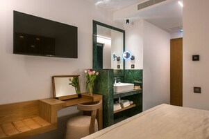Un baño moderno con tocador de madera, un espejo grande, un lavamanos y un televisor montado en la pared.