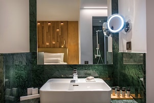 Un baño moderno con un espejo grande, un lavamanos y una ducha.