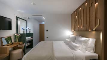 A modern hotel room with a large bed, a desk with a chair, a mirror, and a vanity with a mirror.