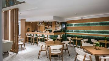 Een modern restaurant met houten meubels, een bar en een groene, gestructureerde wand.