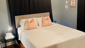 Une chambre à coucher comprenant un lit, une table de chevet, un ventilateur de plafond et des éléments décoratifs sur les murs.