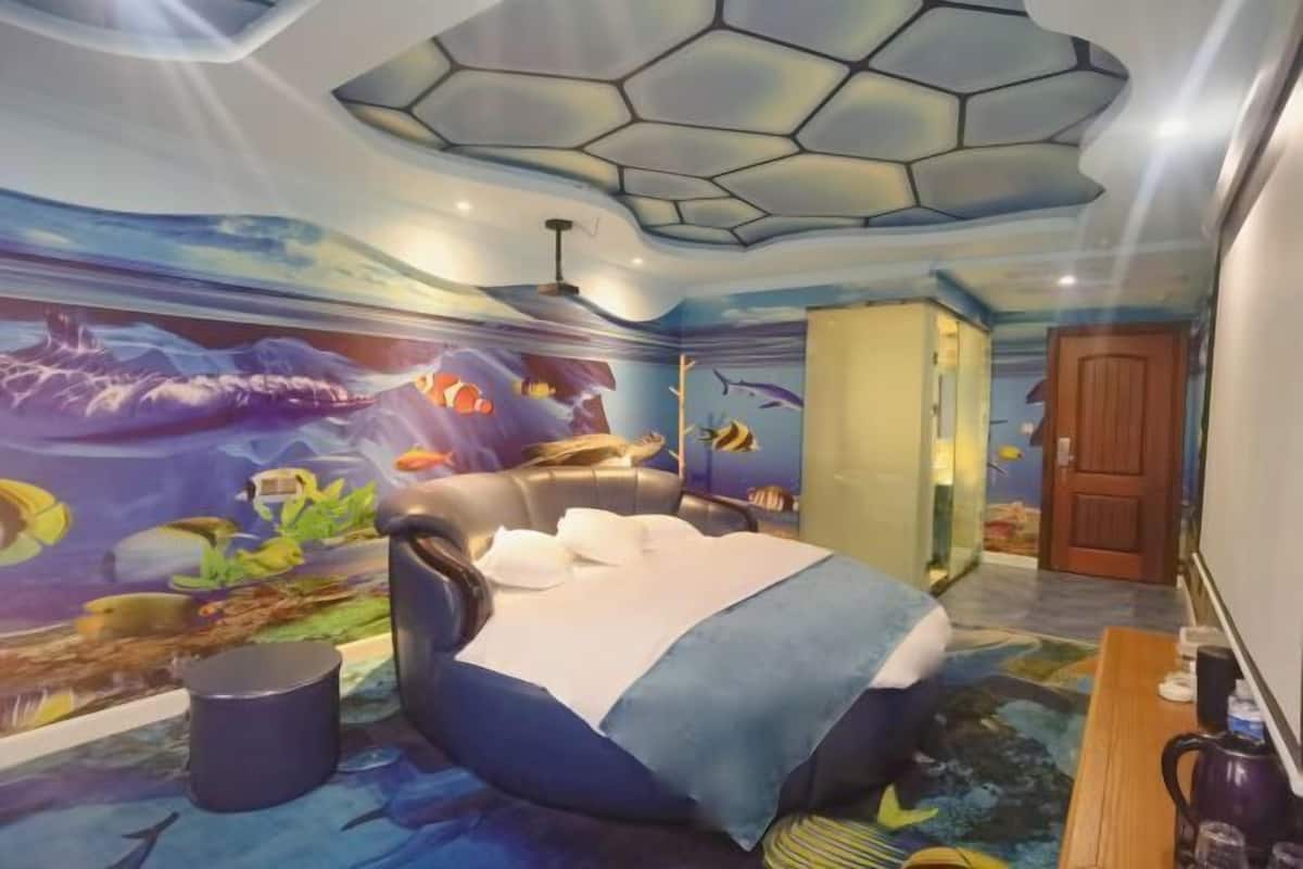Ein Zimmer mit einem Bett, einem Schreibtisch und einem Wandbild einer Unterwasserwelt.