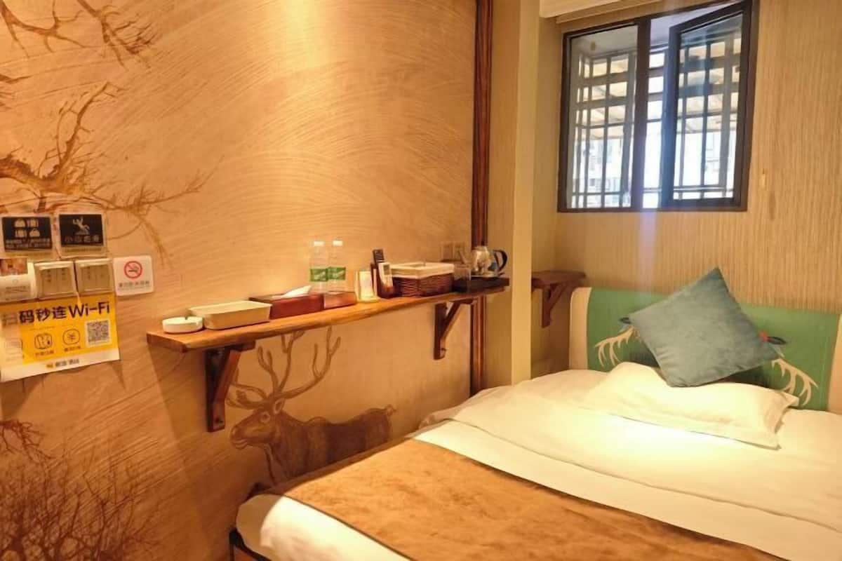 Ein Hotelzimmer mit einem Bett, einem Regal mit Pflegeprodukten, einem Fenster mit Blick und einer Wand mit einem Ast-Design.