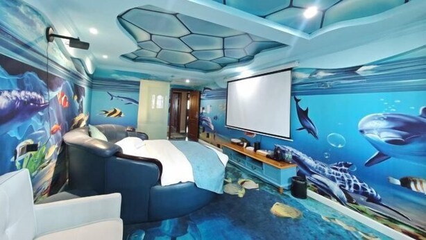 A room with a blue ocean-themed mural, a projector screen, and a seating area. - Edge Point Voice Intelligent Hotel (Chongqing)