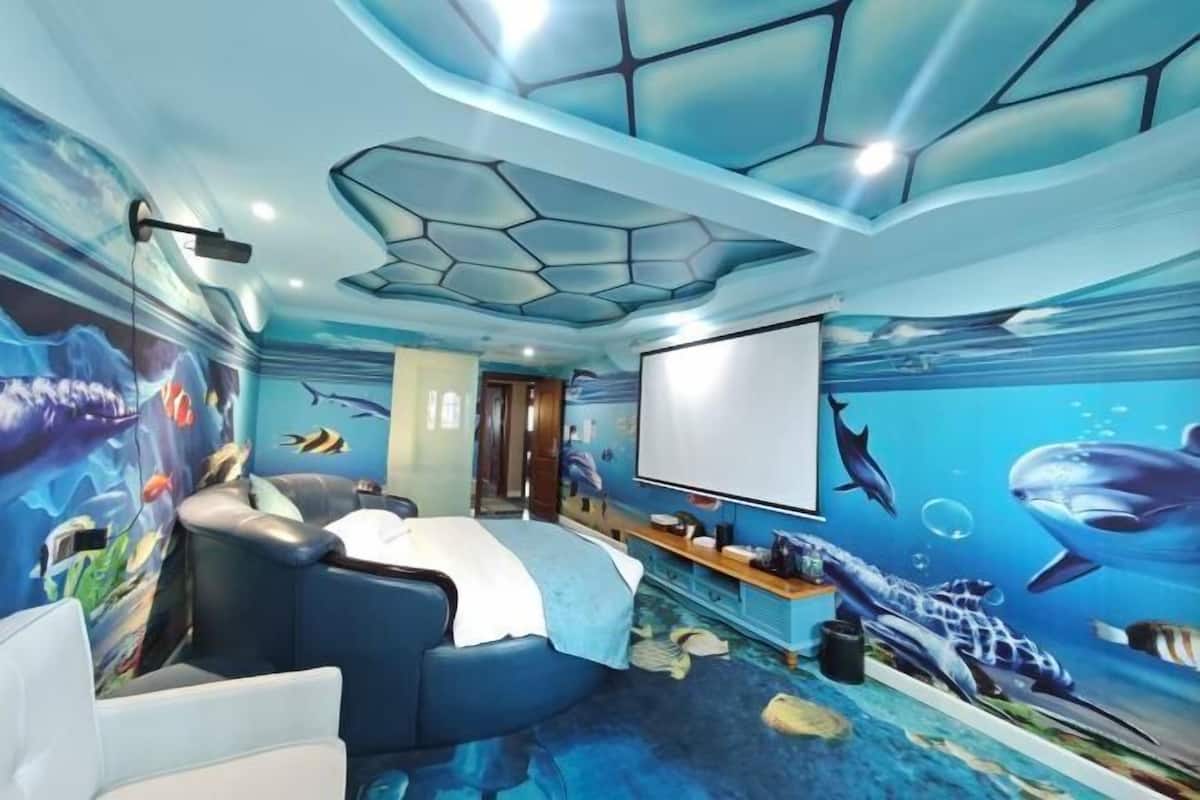 Ein Zimmer mit einem blauen Wandgemälde im Meeresthema, einer Projektionsleinwand und einer Sitzecke.