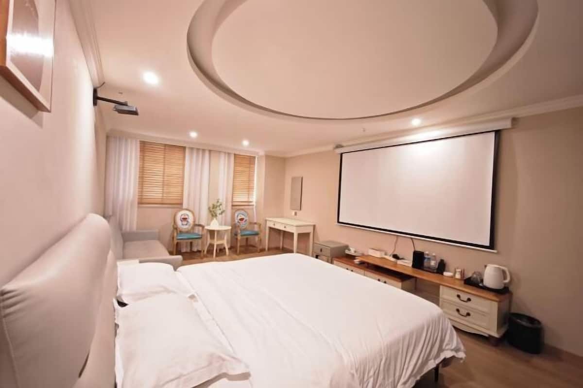 Ein Schlafzimmer mit Bett, Schreibtisch, Stuhl, Fernseher und einem runden Deckenmuster.