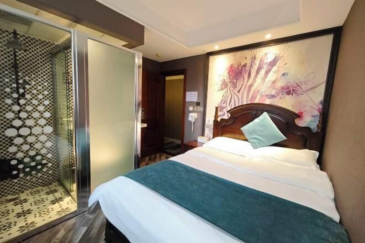 Ein Hotelzimmer mit Bett, Dusche und einem Gemälde an der Wand.