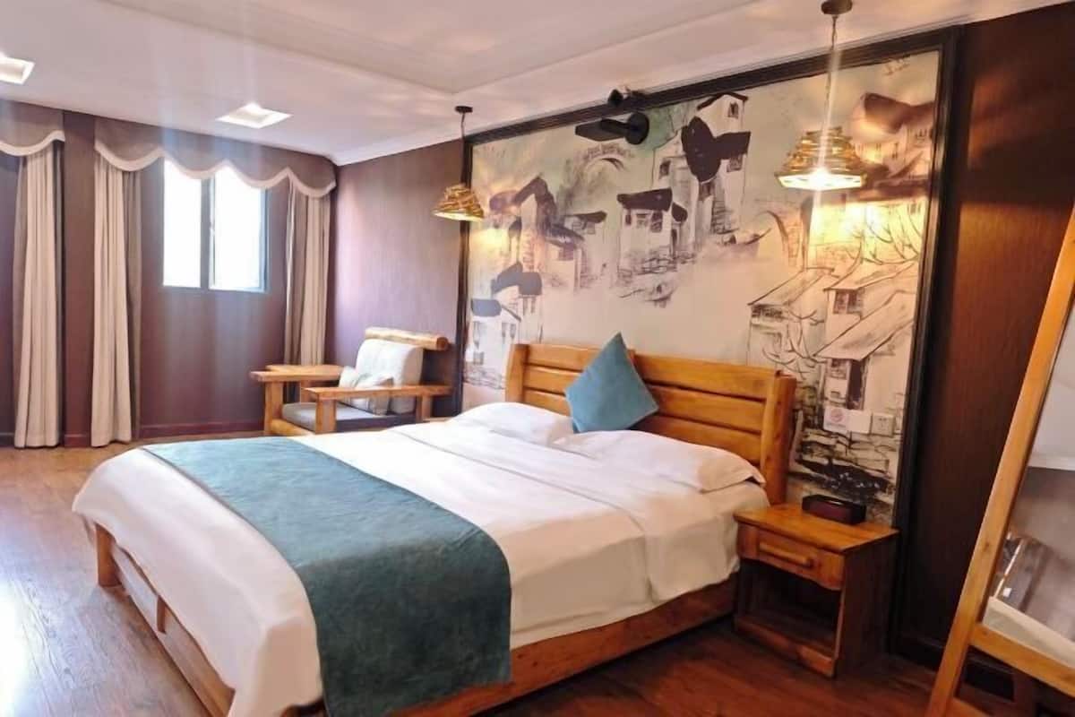 Ein Schlafzimmer mit einem großen Bett, einem Nachttisch, einem Sessel und einer Wand mit Wandgemälde.