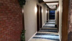 A hallway with a striped floor, brick walls, and doors leading to rooms. - Edge Point Voice Intelligent Hotel (Chongqing)