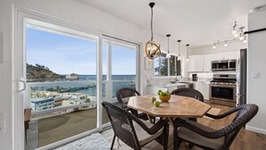 A modern kitchen with a view of the sea, a dining area with wicker chairs, and a large window.