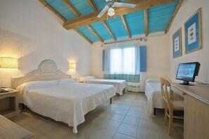 A hotel room with two beds, a desk with a computer, a chair, and a ceiling fan.