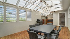 Eine überdachte Terrasse mit Tisch, Stühlen, einem Grill und einem Moskitonetz.