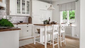 Una cocina moderna con muebles blancos, encimera de madera y ventana con vistas a la vegetación.