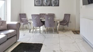 Un espace repas avec un sol en marbre, un canapé gris et un tapis noir.