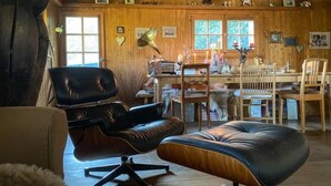 Ein gemütliches Blockhaus-Interieur mit Essbereich, einem schwarzen Ledersessel und einem Holztisch.