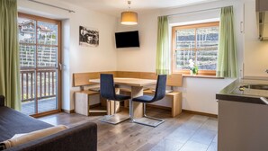 A modern kitchen with a dining area, a TV, and a window with curtains. - Apartment "Gojer Sauvignon" with Mountain View, Garden & Wi-Fi (Cornedo all´Isarco)