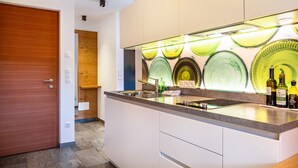 Una cucina moderna con isola integrata, una porta in legno e un lampadario a parete.