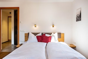 A hotel room with a double bed, two bedside tables, a headboard, and two wall-mounted lights.