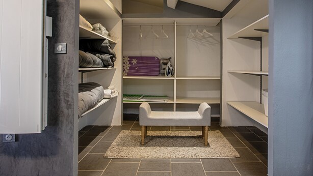 A walk-in closet with shelves, a bench, and a hanging rod.