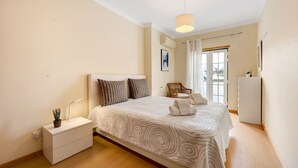 A bedroom with a bed, bedside table, lamp, and a view of the outside. - Holiday Apartment "Tourismer Centro" in City Center with Shared Terrace & Wi-Fi (Lagos)