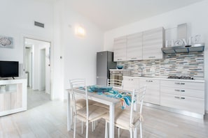 A modern kitchen with white cabinetry, a built-in stove, and a tiled backsplash.
