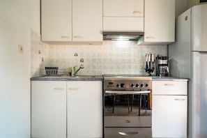 A kitchen with white cabinets, a stove, and a refrigerator.