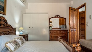 Een slaapkamer met een bed, een dressoir, een spiegel en een kledingkast.