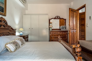 A bedroom with a bed, dresser, mirror, and wardrobe.