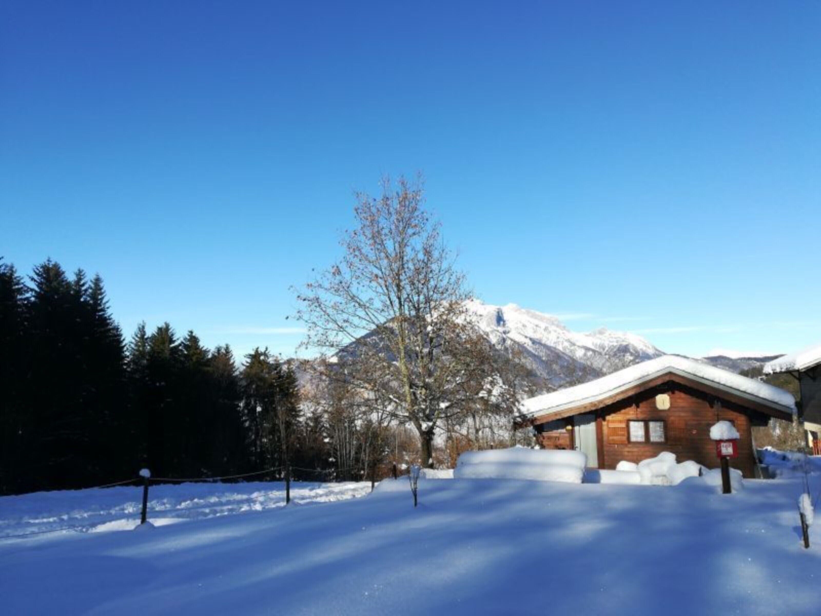 Un paysage enneigé avec une cabane en bois et une montagne en arrière-plan.