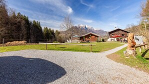 A mountain lodge with a gravel path leading to a wooden deck, surrounded by trees and a clear sky. - Chalet "Sauvage" with Mountain Views, Private Terrace and Wi-Fi. (FAVERGES-SEYTHENEX)