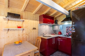 Eine kleine Küche mit Holzwänden, einem roten Kühlschrank, einer Mikrowelle und einem Spülbecken.