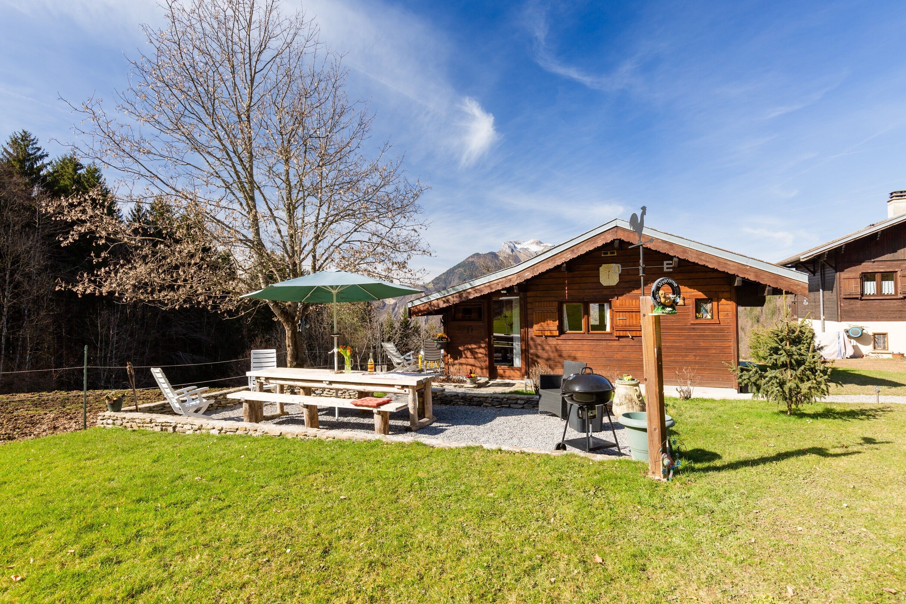 A wooden cabin with a patio, outdoor seating, and a barbecue grill.
