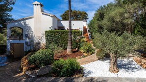 Un edificio bianco con tetto in tegole, una palma e una scalinata che conduce a una porta.