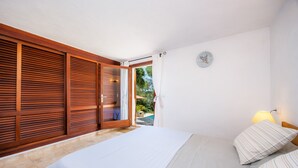 Una camera da letto con un letto, persiane di legno, vista sull'esterno e una sveglia a parete.