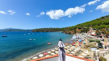 Blick auf die Küste mit Strand, Sonnenschirmen und Booten.