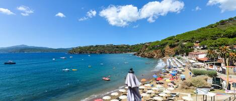 A coastal view with a beach, umbrellas, and boats.