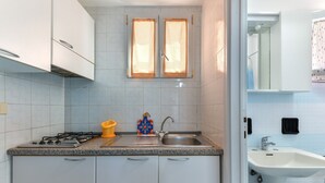 A kitchen with a gas stove, sink, and cabinets. - Apartment 'Villa Oda - Monolocale Sul Mare' with Sea View, Wi-Fi and Air Conditioning (Capoliveri)