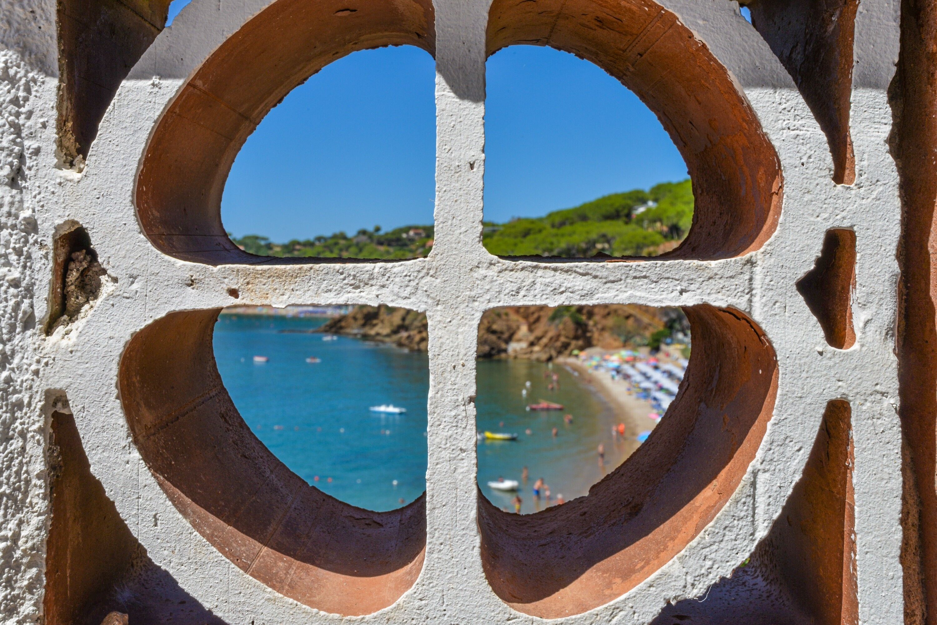 A coastal view through a window with a white frame and four arches.