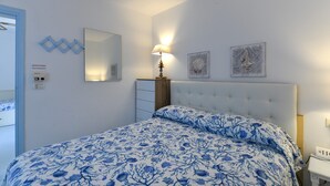 Une chambre à coucher comprenant un lit, une lampe de chevet, une commode et des œuvres d’art accrochées au mur.