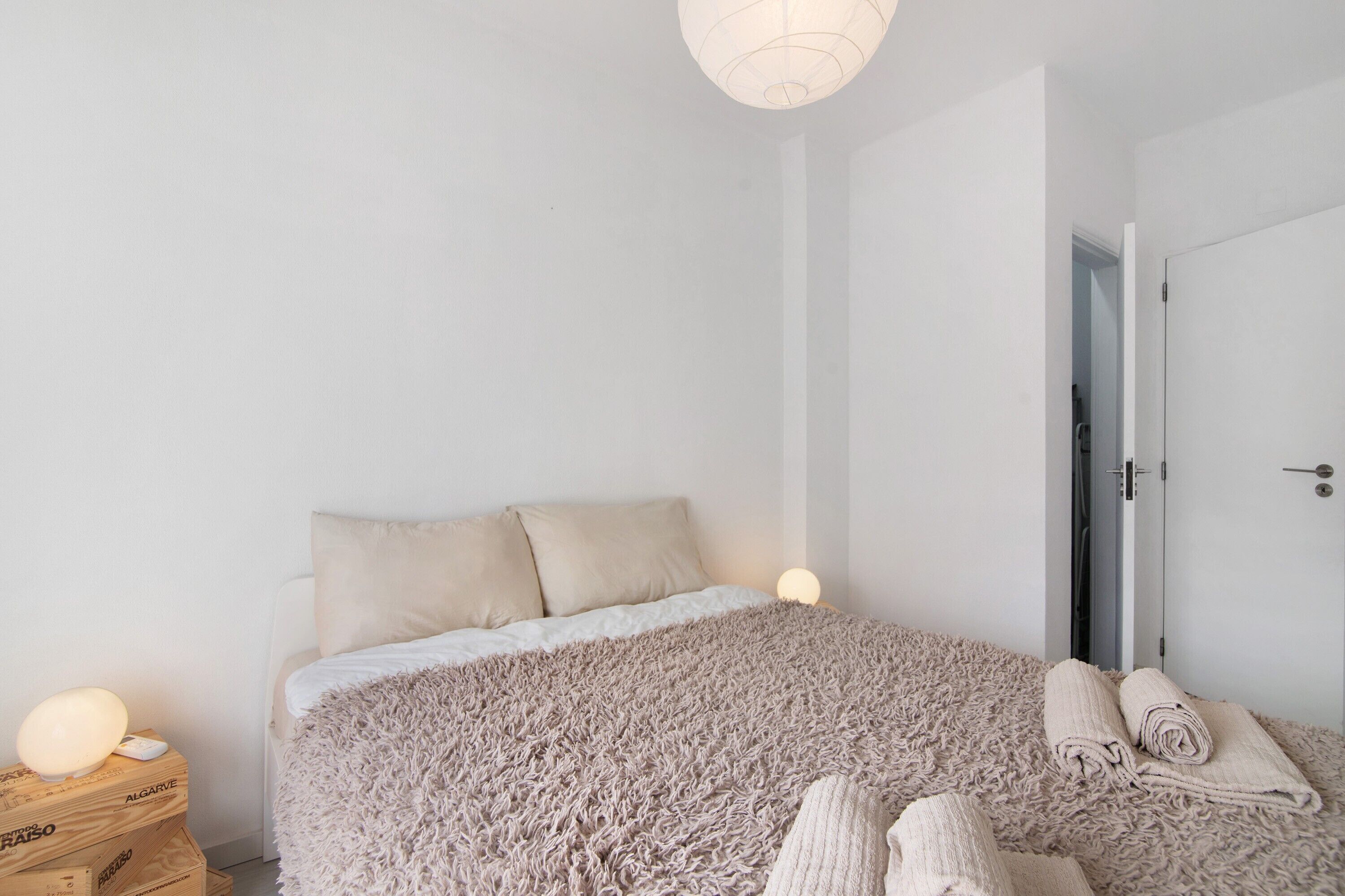 Une chambre avec un grand lit, une lampe de chevet, une porte et une serviette sur le lit.