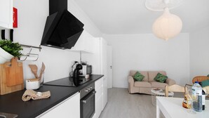 Une cuisine moderne avec un plan de travail noir, une machine à café et un téléviseur.