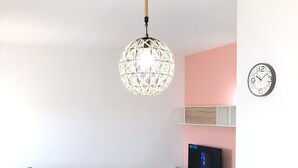 Una sala de estar moderna con un sofá verde, una mesa de comedor blanca y una lámpara esférica colgante.