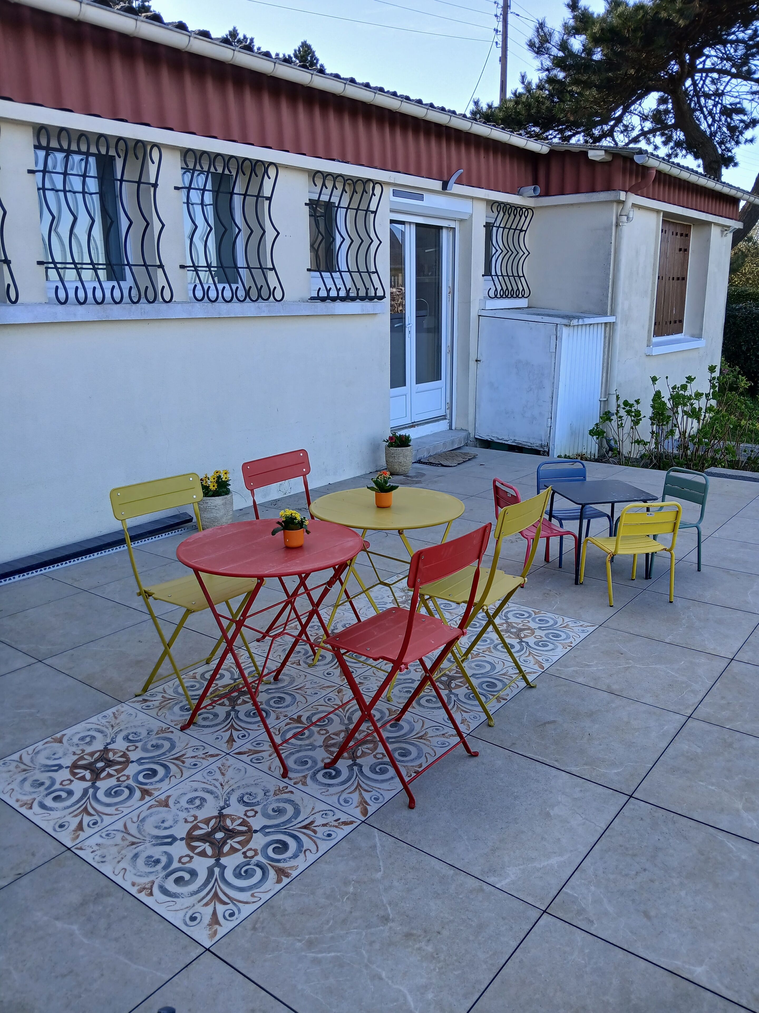 A patio area with outdoor furniture, including tables and chairs, and a decorative tile pattern on the floor.