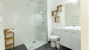 A modern bathroom with a glass-enclosed shower, a white toilet, and a vanity with a mirror.