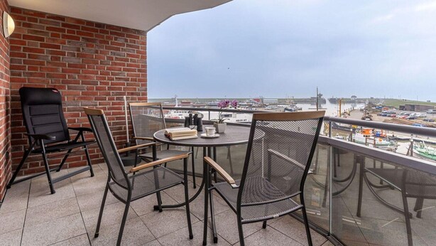 Een balkon met een bakstenen muur, een ronde tafel en vier stoelen.